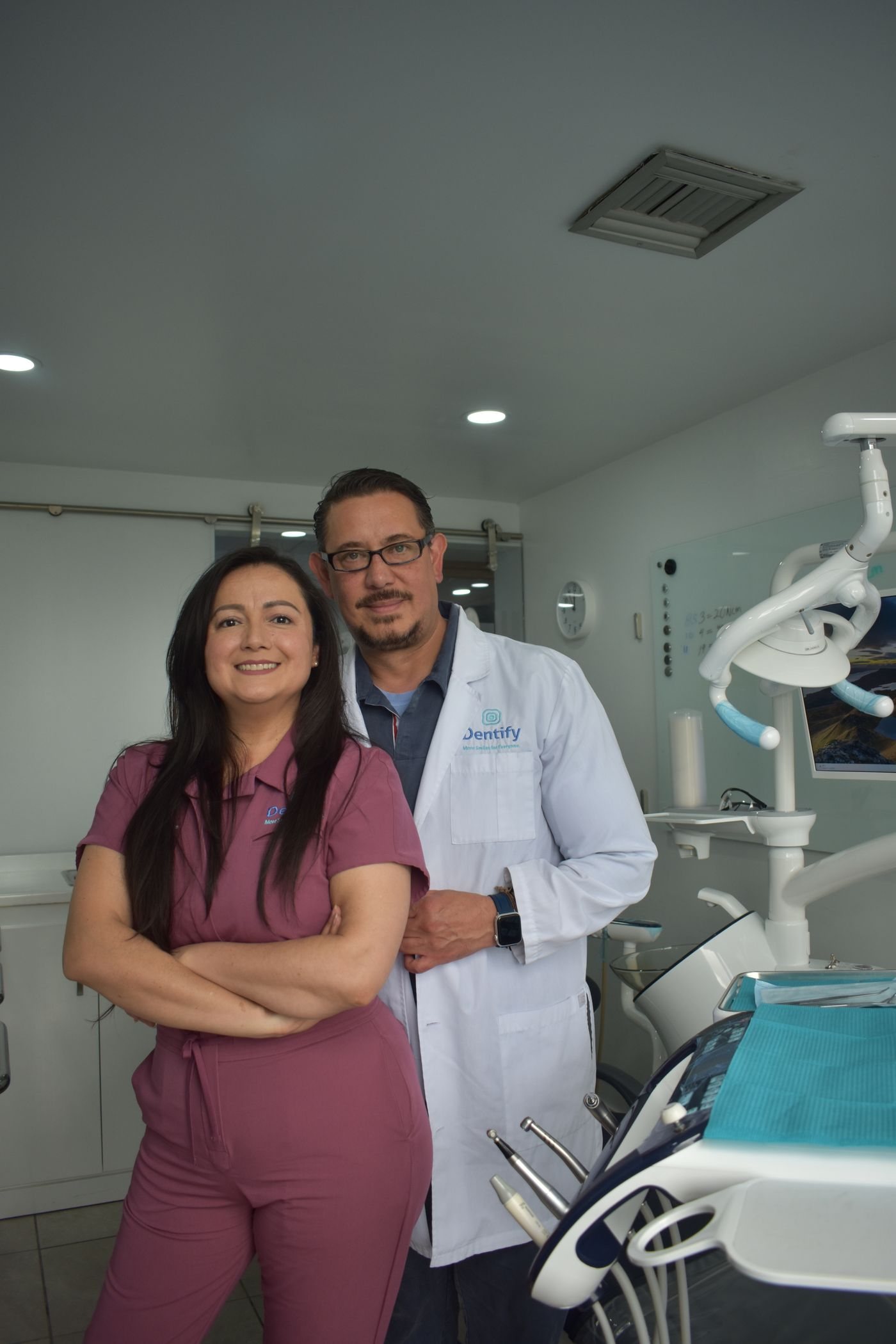 Two dental professionals standing together in a practice, turned toward the camera.